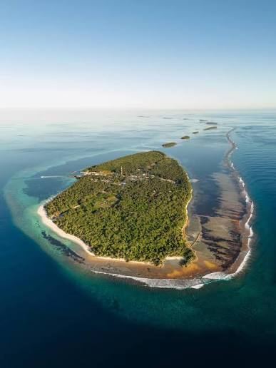 Aerial view of Kondey in Huvadhu Atoll: a green palm canopy ringed by white sand, lagoon and reef